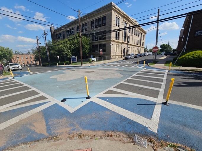 An intersection mural in Belleville, NJ created a more safer crossing environment for people walking near a school using only paint and flex-posts. (Source: NJDOT Bicycle & Pedestrian Resource Center)